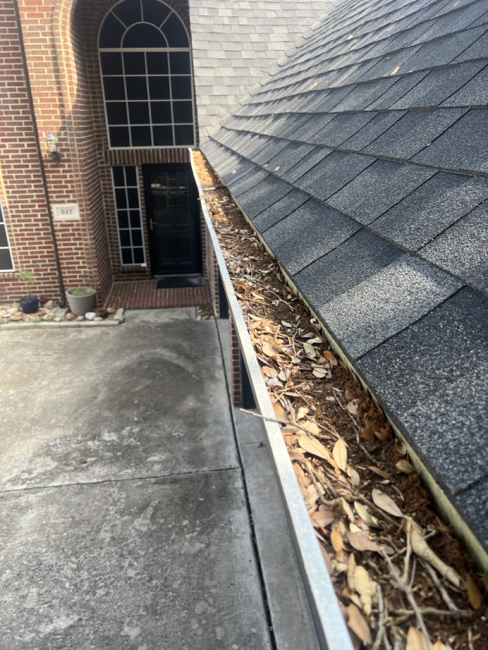Clogged gutter full of leaves and debris before gutter cleaning service